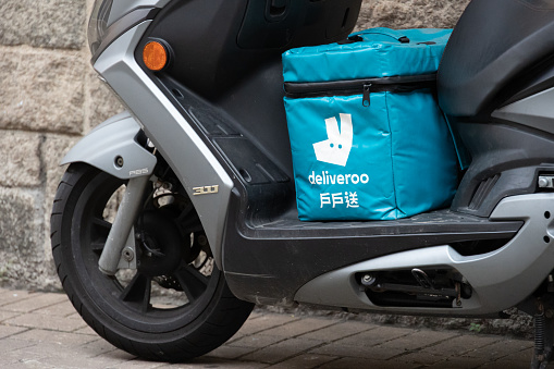 Hong Kong - May 23, 2022 :  A motorbike is seen parked on the street carrying an insulated food bag from the delivery take out food company Deliveroo in Hong Kong.