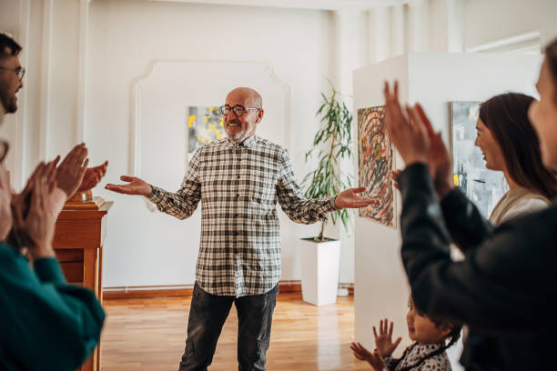 People at gallery opening People applauding to a mature male artist at gallery opening. gallery opening stock pictures, royalty-free photos & images