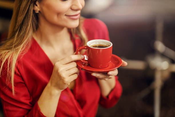 istock A woman holding cup of coffee next to a roasting machine. 1398802684