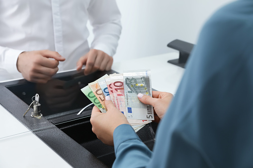 Woman with money at cash department window, closeup. Currency exchange