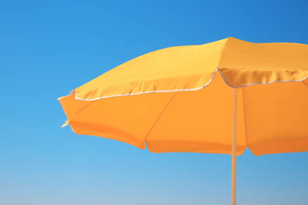 istock Orange beach umbrella against blue sky on sunny day 1398804323