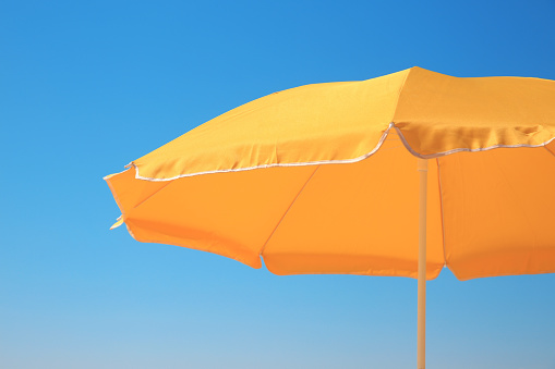 Orange beach umbrella against blue sky on sunny day