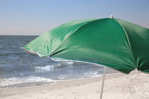 Green beach umbrella near sea on sunny day