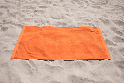 Beautiful soft orange beach towel on sand