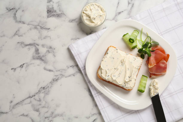 istock Delicious sandwich with cream cheese, cucumber and jamon on white marble table, flat lay. Space for text 1398805056