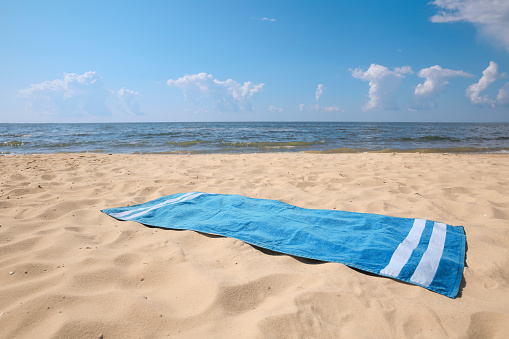 Blue striped beach towel on sandy seashore