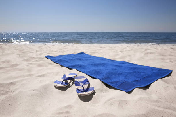 Flip flops and blue beach towel on sandy seashore