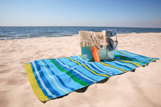 istock Striped beach towel and bag with accessories on sandy seashore 1398805327