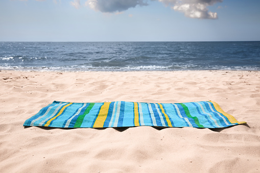 Bright striped beach towel on sandy seashore