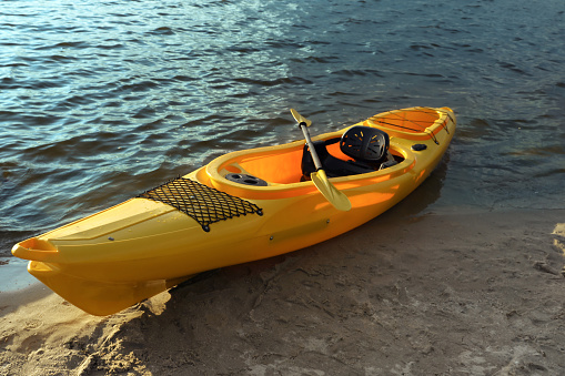 Beautiful modern yellow kayak with paddle on beach