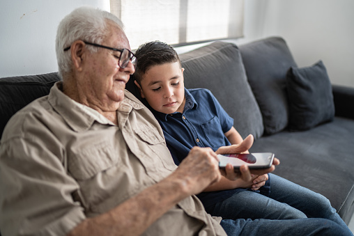 Grandfather and grandson using mobile phone at home