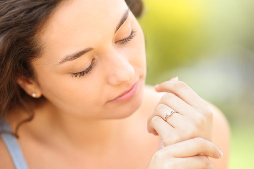 Serious woman looking at engagement ring in a park