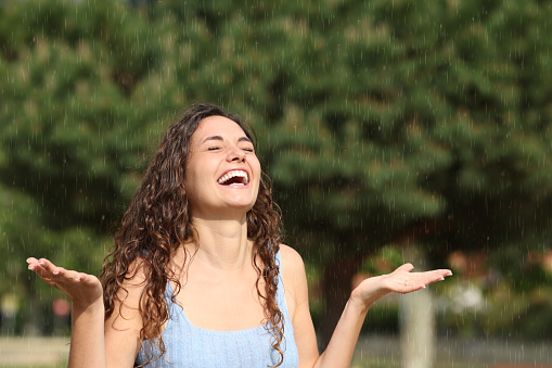 Happy woman enjoying under rain a sunny day
