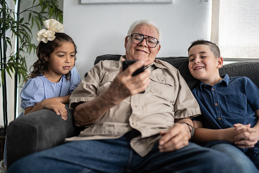 Grandfather with grandchildren using mobile phone at home