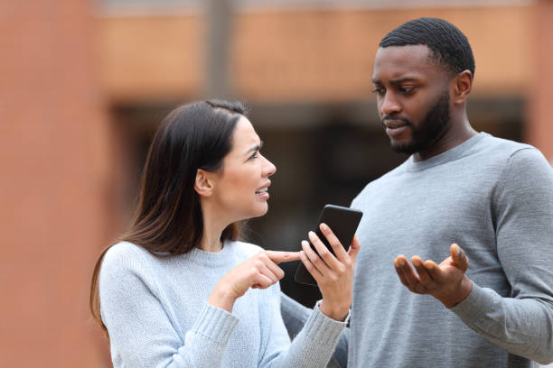 Woman asking for explanation about phone text to a man stock photo