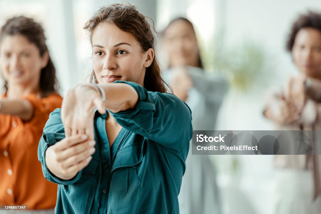 Businesswomen Stretching in the Office Group of diverse businesswomen stretching in the office during the break Office Stock Photo