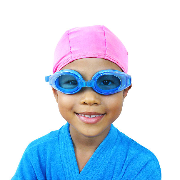 Female swimmer wearing swimming cap and goggles. She is looking away with a toothy smile in front of white background.