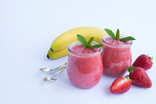 Smoothie with strawberry and banana in the glass jar on the white background. Copy space. Close-up.