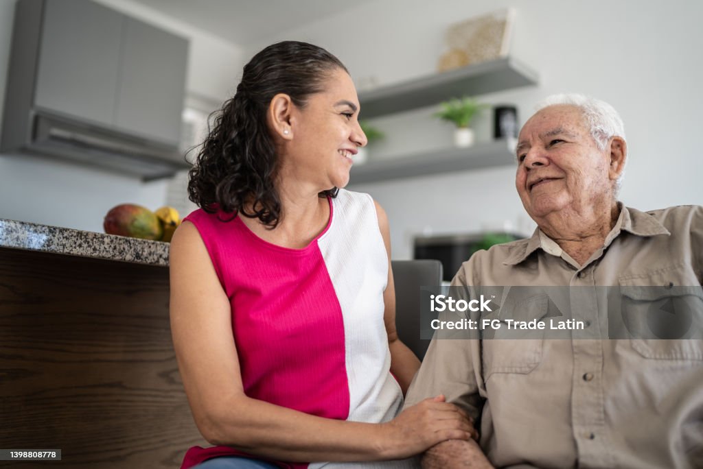 Senior man and his daughter (or home caregiver) talking at home Senior man and his daughter talking at home Senior Adult Stock Photo