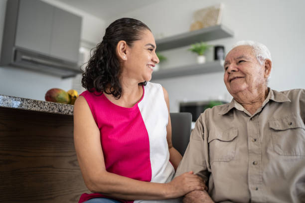 Senior man and his daughter (or home caregiver) talking at home stock photo