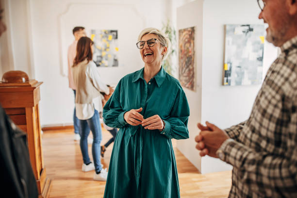 People discussing art Diverse group of visitors in modern art gallery having a discussion with female artist. gallery opening stock pictures, royalty-free photos & images