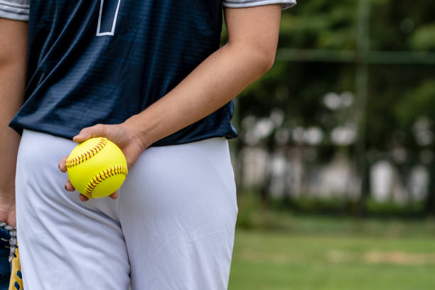 A young Softball player ready to peatch from his position in the outfield.holding a Softball ball in his hands while playing catch in the outfield stock photo