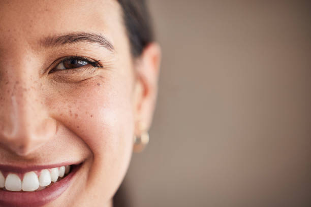 Rostro de hermosa mujer de raza mixta sonriendo con dientes blancos. Retrato de la cara de una mujer con ojos marrones y pecas posando con espacio de copia. Salud dental e higiene bucal - foto de stock