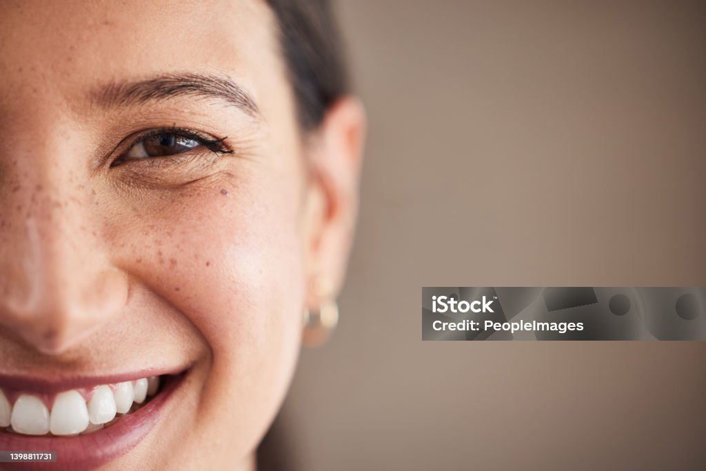 Face of beautiful mixed race woman smiling with white teeth.  Portrait of a woman's face with brown eyes and freckles posing with copy-space. Dental health and oral hygiene Smiling Stock Photo