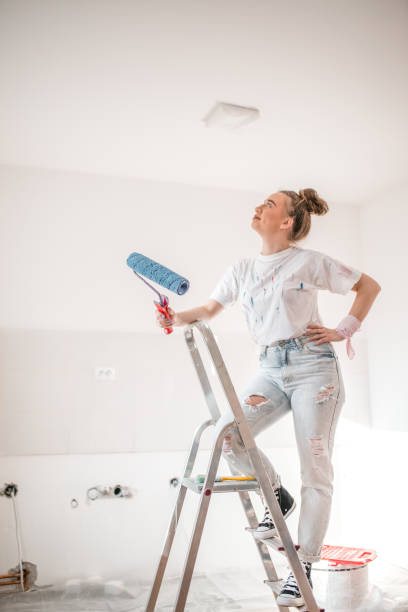 istock Woman standing on a ladder and thinking how to paint the ceiling 1398812053