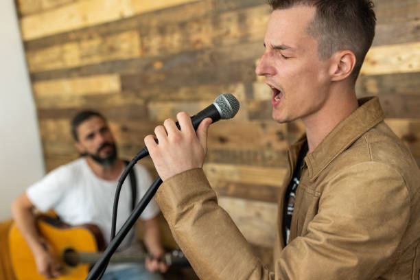 Man singing while his teacher playing acoustic guitar, during music class