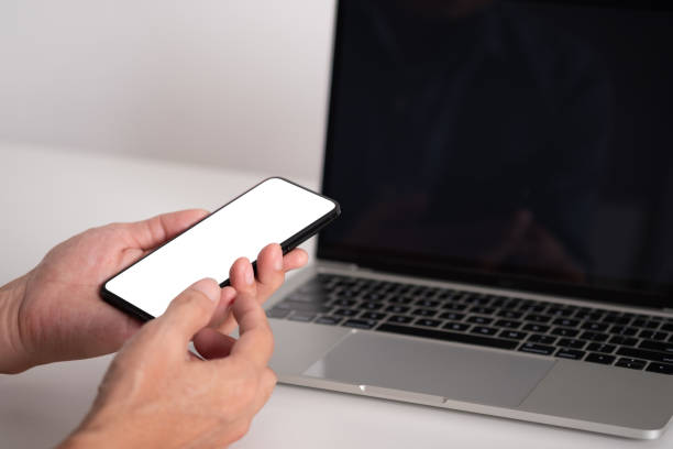 istock Businessman holding blank screen smartphone, people using smartphone with laptop on white table office 1398813810