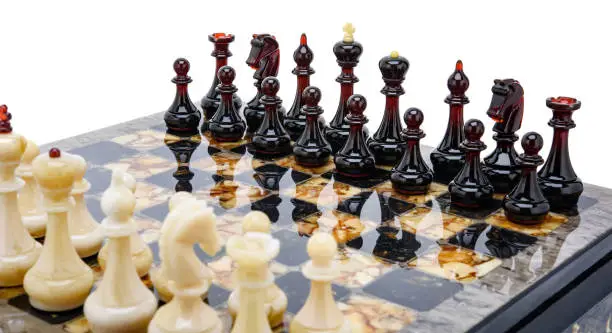 Natural amber different chess pieces figures standing on lacquer surface board on white. Close up game concept competition, Classic Tournament of confrontation.