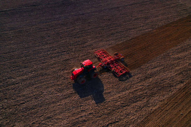 istock Tractor disk harrow on ploughing a soil. Sowing seed on plowed field on sunset. Seeding in agriculture. 1398815231