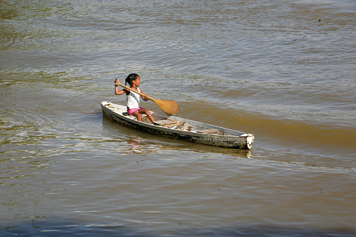 Young girl riding a wooden canoe alone in the Guamá River, part of the Amazon River, near Belém, Pará, Amazon, Brazil. January, 2008.