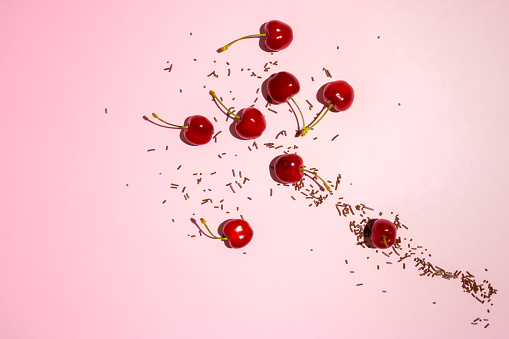 Cherries with chocolate crumbs on pastel pink background. Creative food or nature concept.