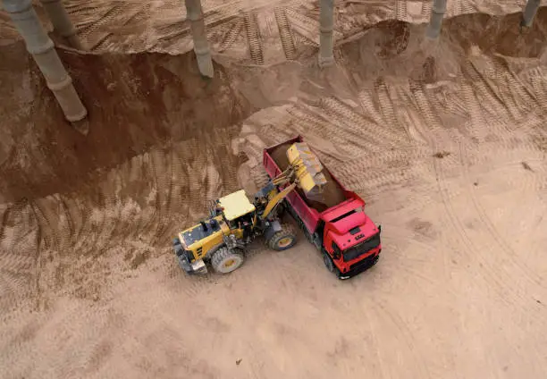 Photo of Wheel loader load sand in tipper truck in open pit.