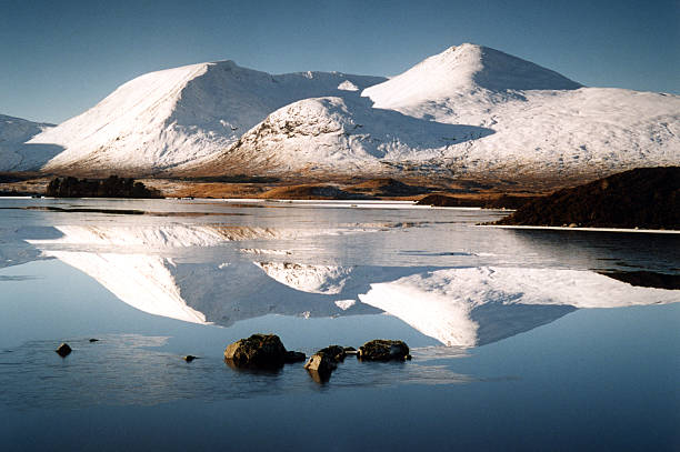 Rannoch Moor (Scotland) Rannoch Moor, Scotland, Scottish Highlands, near Glencoe. Mountains with white top reflects in the mirror of the lake. Three small stones are in a foreground. Winter, January, sunny day. buachaille etive beag photos stock pictures, royalty-free photos & images