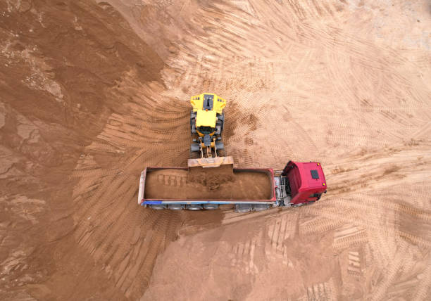 istock Wheel loader load sand in tipper truck in open pit. Front end loader on earthworks in open-pit mining. 1398818007