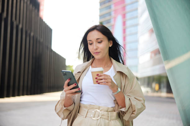 Close-up view of a businesswoman with a smartphone and a coffee cup. stock photo