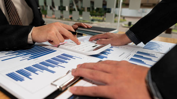 istock Two business people analyze a graph of financial data and a laptop computer. Corporate financial investment advisor concept image for the stock market, office, tax, and projects. 1398820582