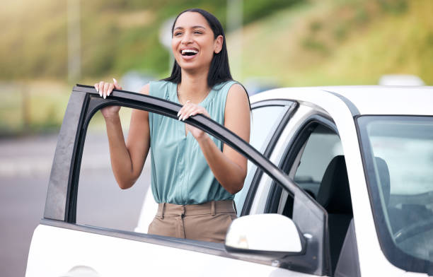 alegre mujer de raza mixta conduciendo su nuevo coche. mujer hispana que se ve feliz comprando su primer auto o pasando su examen de conducir. mujer hispana relajada sobre el seguro de auto contra el espacio de copia brillante - blank sale young women one young woman only fotografías e imágenes de stock