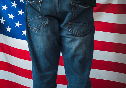 Unrecognizable man from behind in baggy jeans from work with flag of the United States. United States elections concept