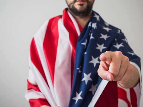 Unrecognizable american man with usa flag and pointing at camera. Election concept