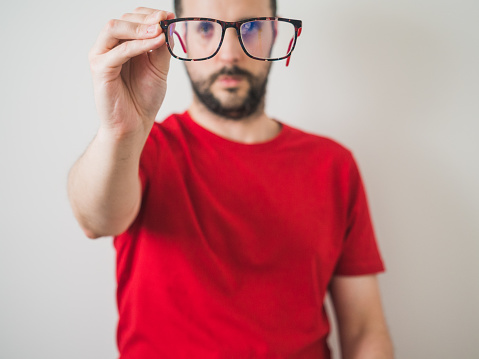 Caucasian man with vision problems holding reading glasses. Optical concept