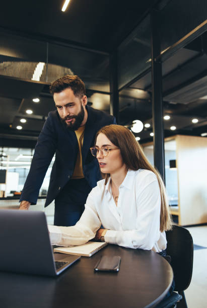istock Coworkers using a laptop together in an office 1398822220
