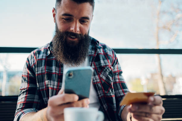 istock Bearded man using smartphone and a credit card in a cafe or restaurant 1398822319