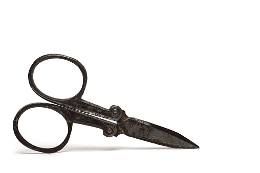 Closeup of a vintage retro heavily used small very old steel metal nail scissors against white background