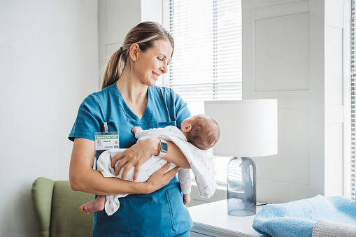 Enfermera pediatra que cuida al bebé recién nacido en la sala del hospital. photo