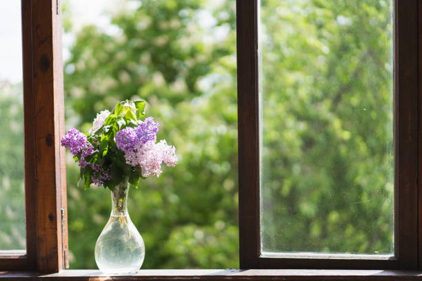 istock Vase with spring flowers lilac on a wooden window. Cozy spring concept 1398823596