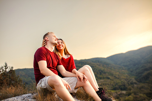 Young couple resting and admiring the view from the mountain